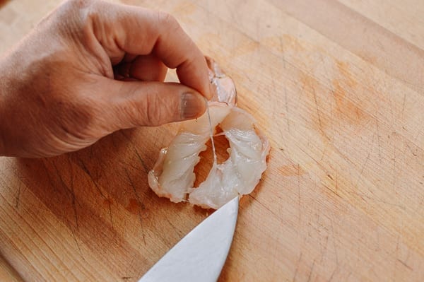 Removing vein from a shrimp that has been sliced in half lengthwise
