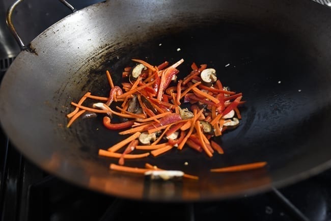 Adding carrots, peppers, and mushrooms to garlic in wok, geagle.miooashdv.tk