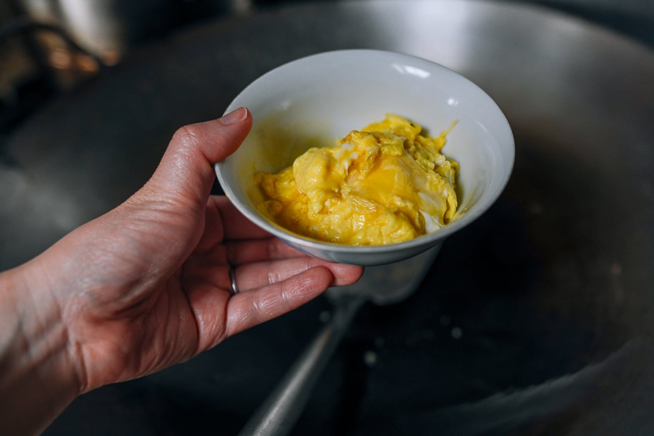 Removing cooked egg from wok to a bowl