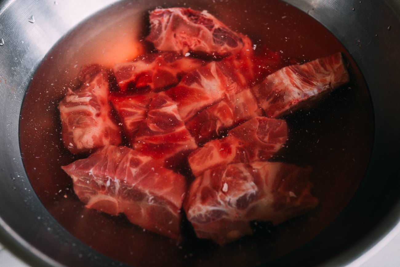 Soaking pork neck bones in water in a large metal bowl