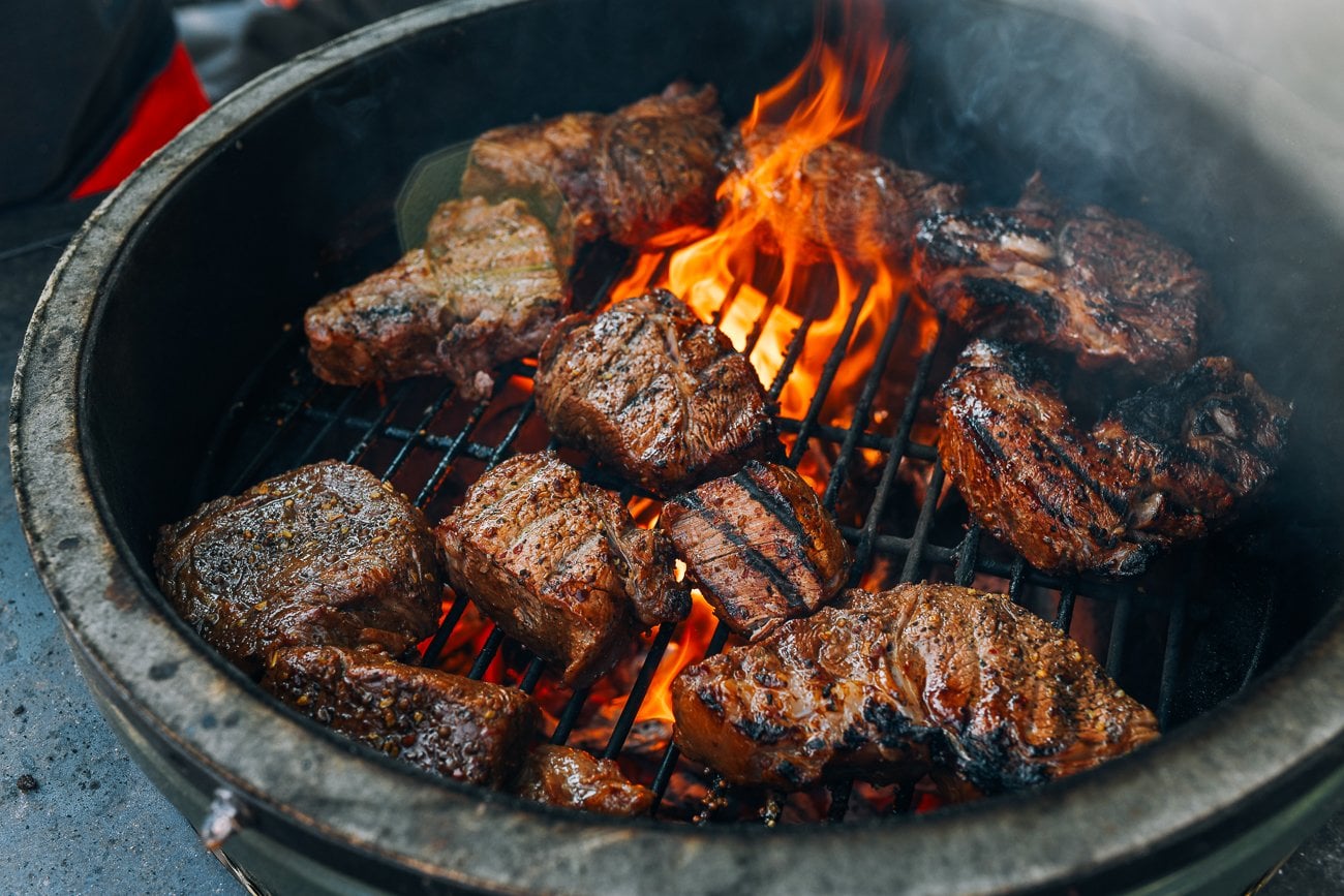 steaks grilling on round kamado style grill