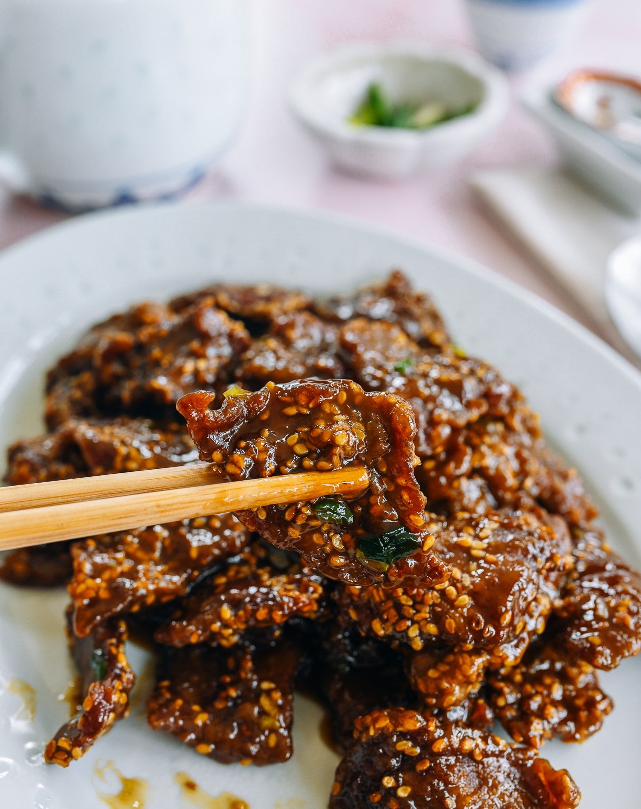 picking up piece of sesame beef with chopsticks