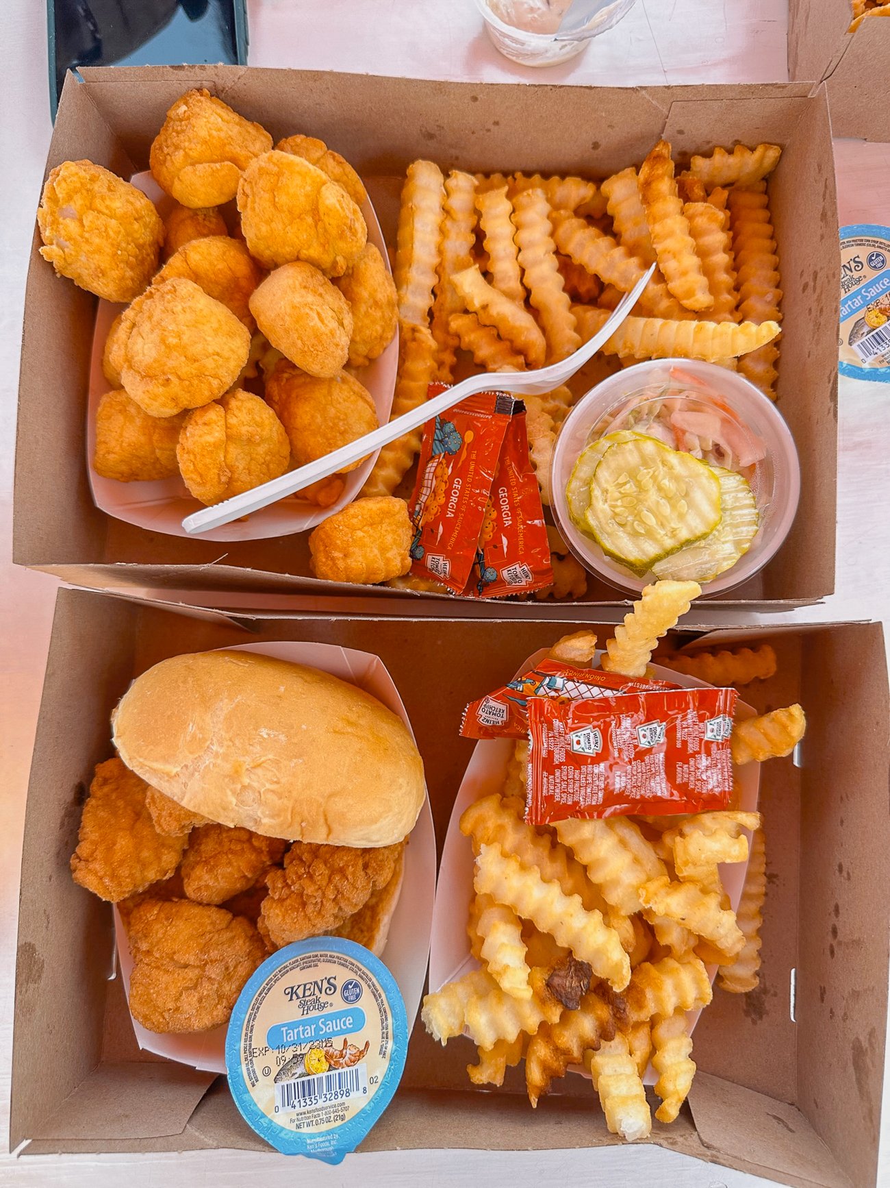 Fried scallops with french fries and a side of pickles and a fried fish sandwich with fries from The Clam Shack in Kennbunkport