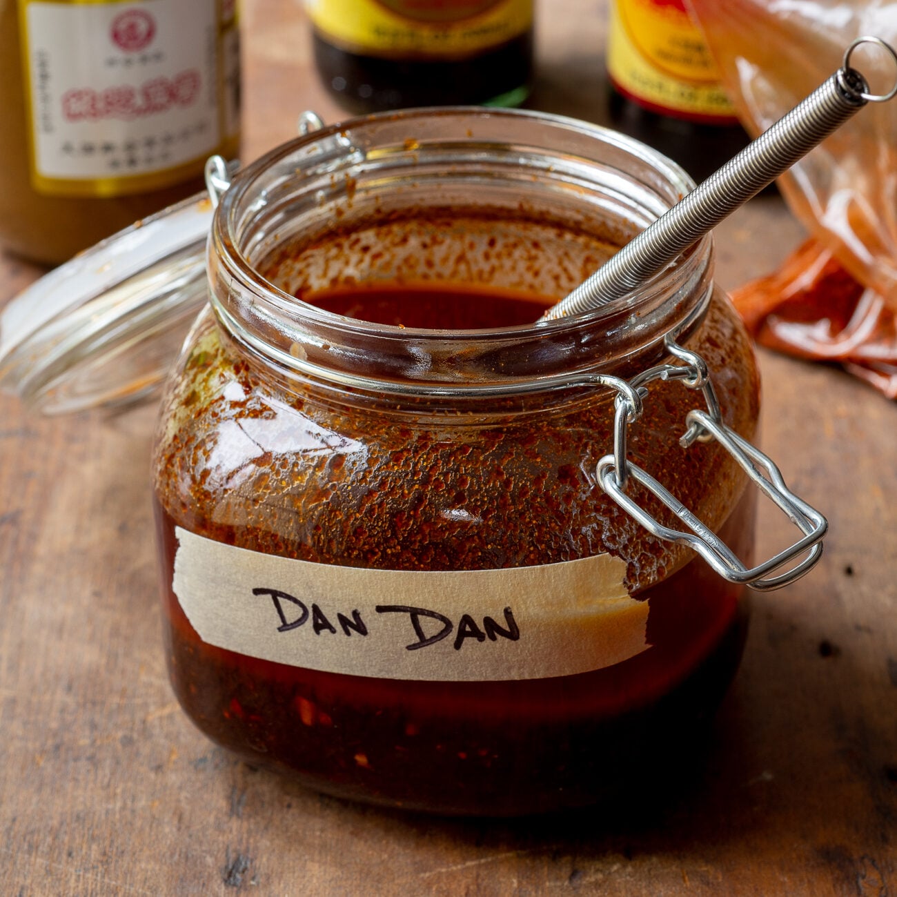 Jar with hinged lid with dark red sauce and masking tape label that says "DAN DAN"