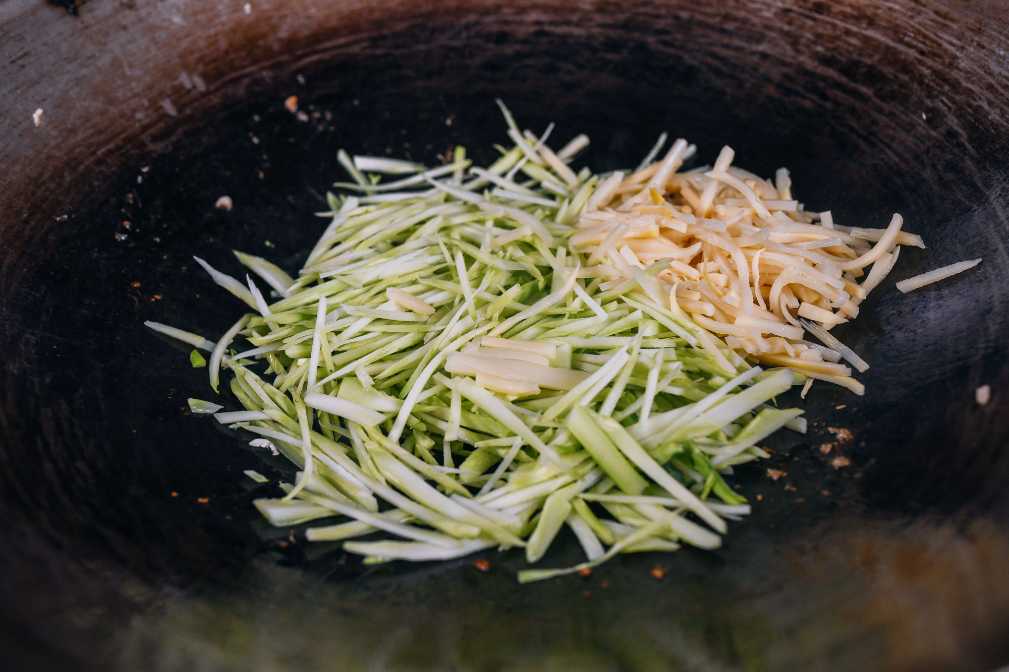 julienne broccoli stem and bamboo shoots in wok