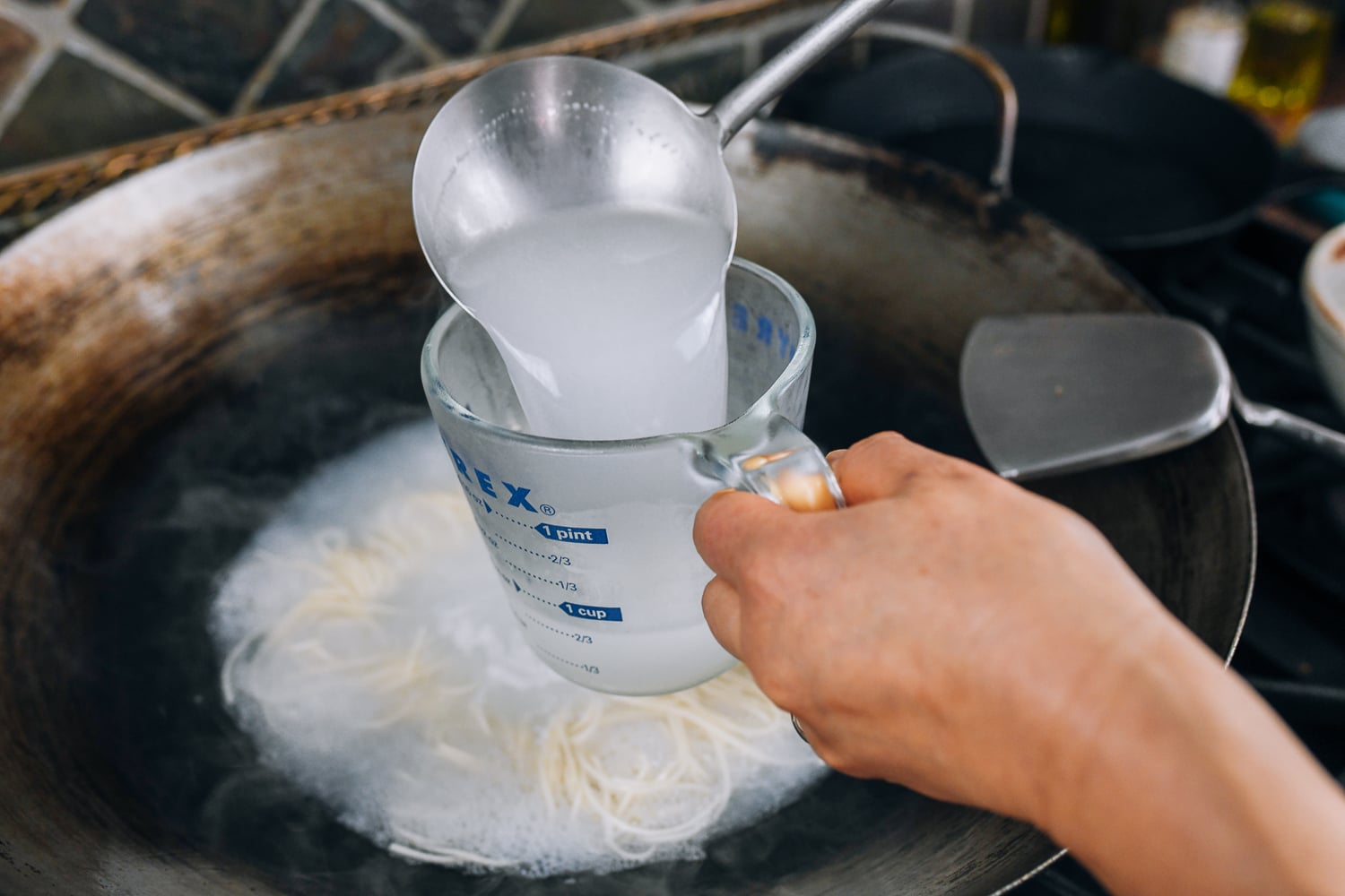 ladling cooking water into measuring cup