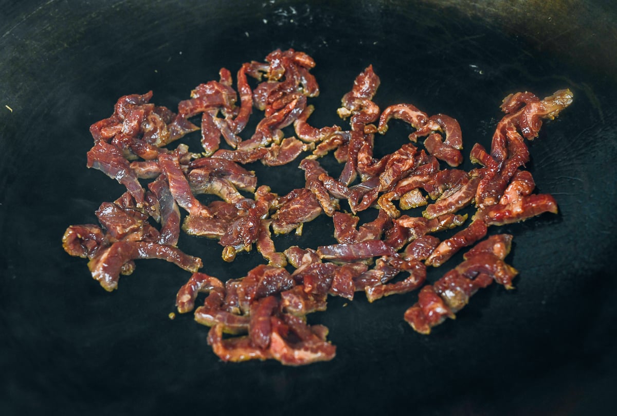 searing marinated beef strips in wok