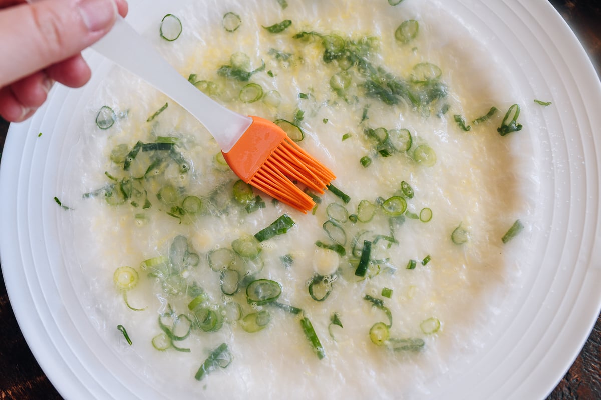 lightly brushing gluten-free scallion pancake with egg
