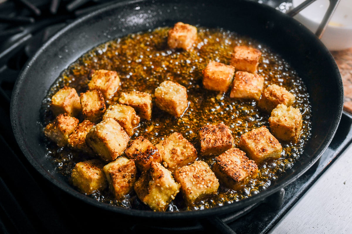tossing crispy tofu in sauce