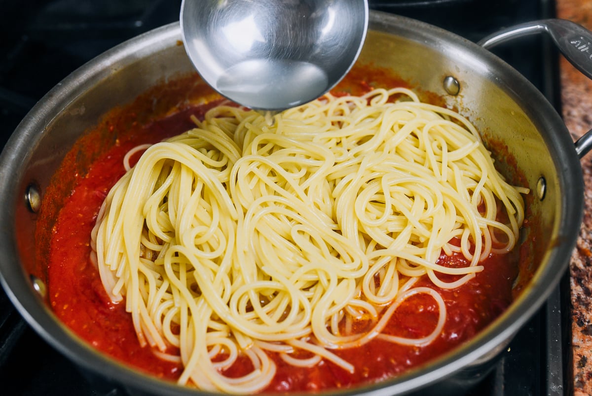 adding pasta water to spaghetti and tomato sauce