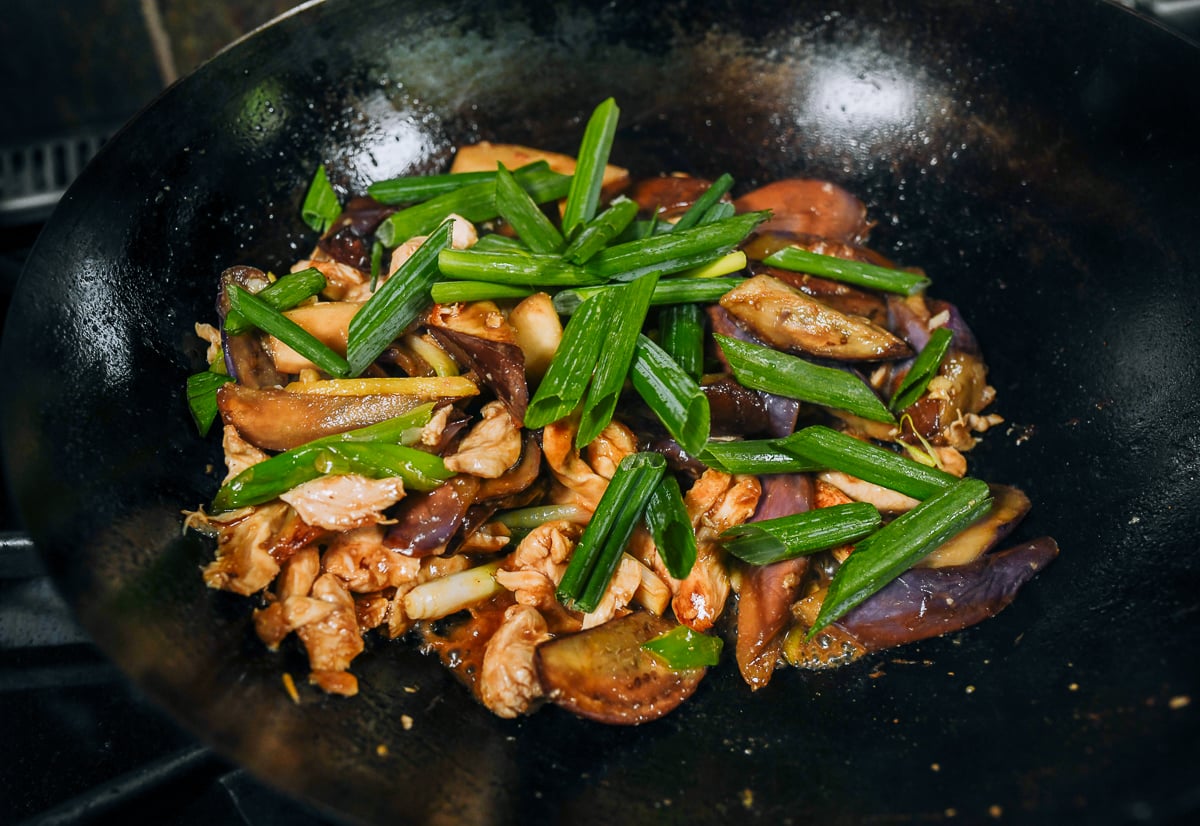 adding green part of scallions to eggplant and chicken